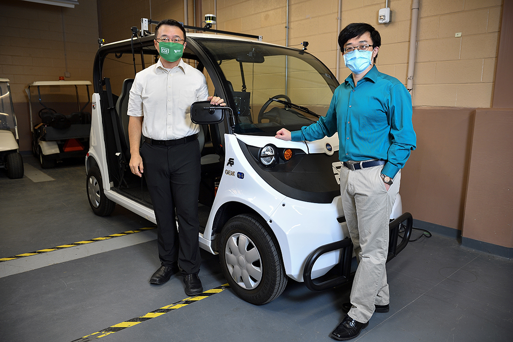 Song Fu and Qing Yang stand in front of an autonomous golf cart