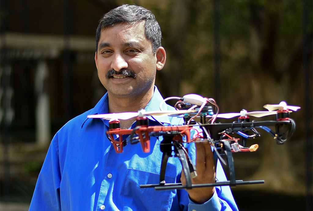 Kamesh Namuduri stands while holding a drone.