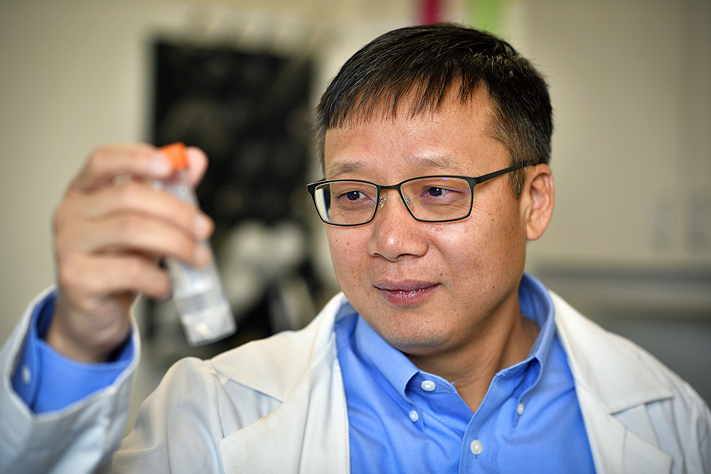 Jincheng Du eyes a sample in a test tube in his lab