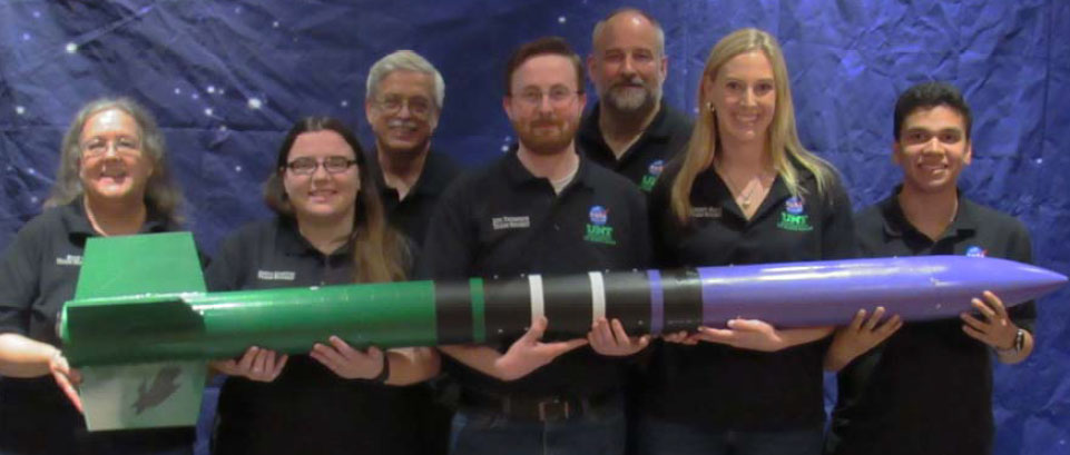 The team poses holding the rocket