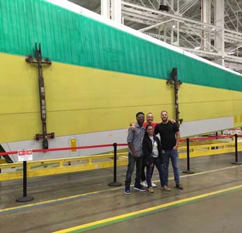Team members poses in front of a large structure