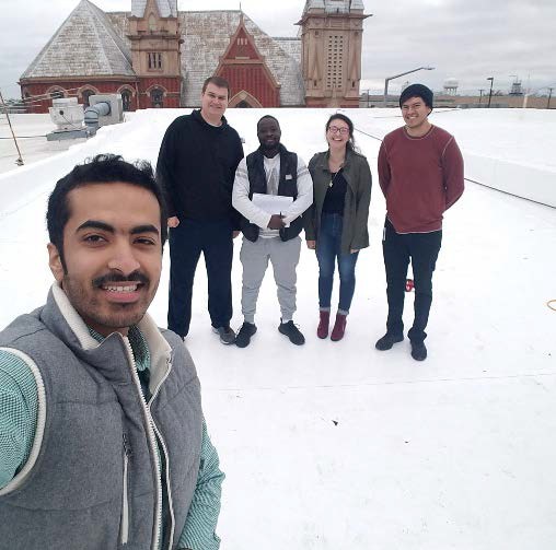 Team members pose on the top of building