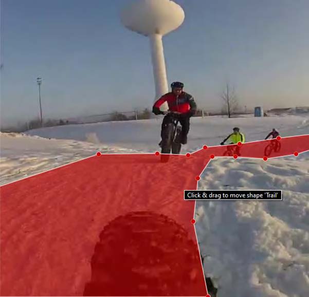 A trail is painted red in a photo where there are three cyclists