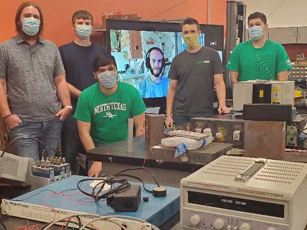 Team members pose with the project setup in the lap