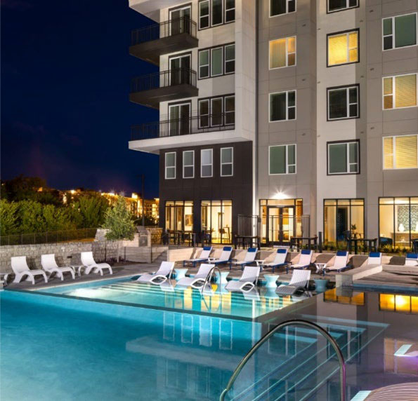 Photo of the aprtment complex with a pool in front of the building