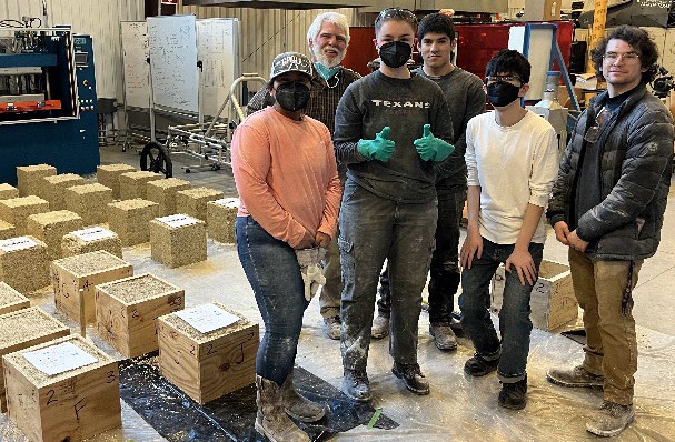 Team members pose with the hempcrete boxes by the side