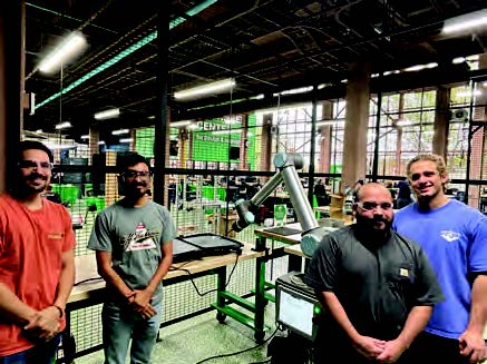 Team members pose with the robotic arm