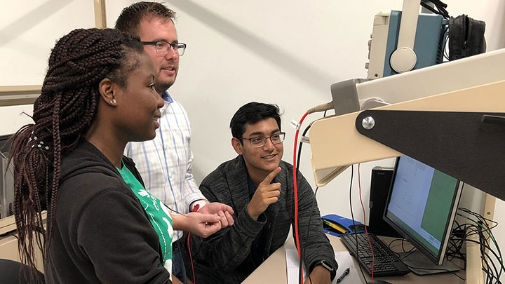 Two male and one female students doing test on human with instrument