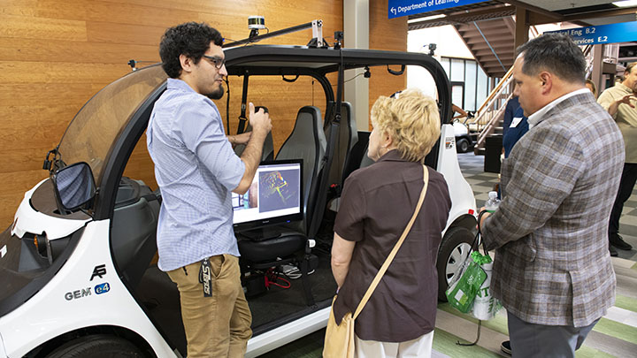 Student researcher presenting autonomous vehicle to visitors