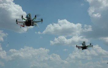 Two black drones flying in the blue sky