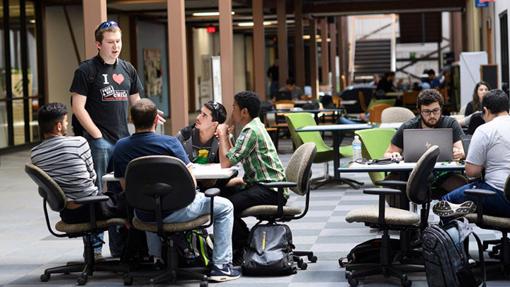 A group of students talking around a table in hallway