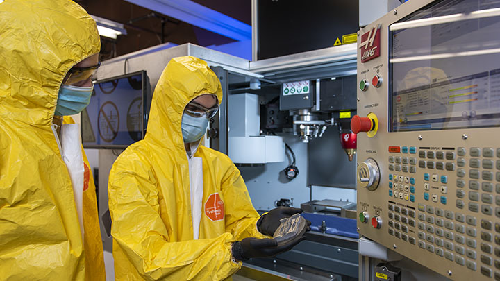 Two researchers in yellow hazmat suit conducting research in lab