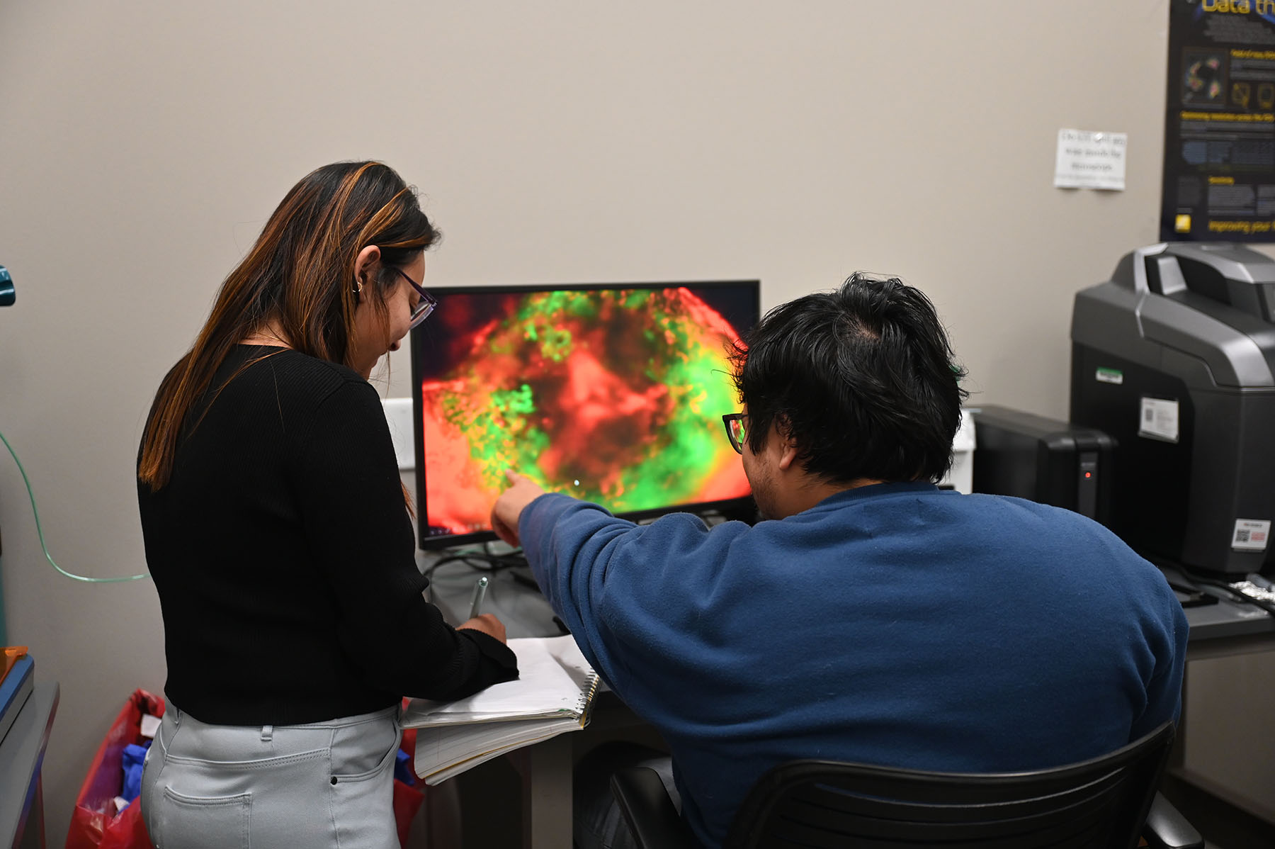 Two students look at computer screen in lab