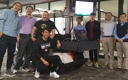 Yang and Fu posing with students in front of golf cart converted autonomous vehicle