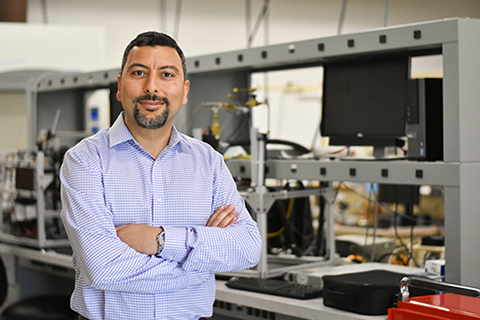 Huseyin Bostanci stands with arms crossed in his lab.