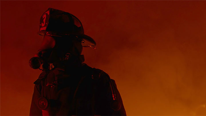 A firefighter with flame and smoke in the background