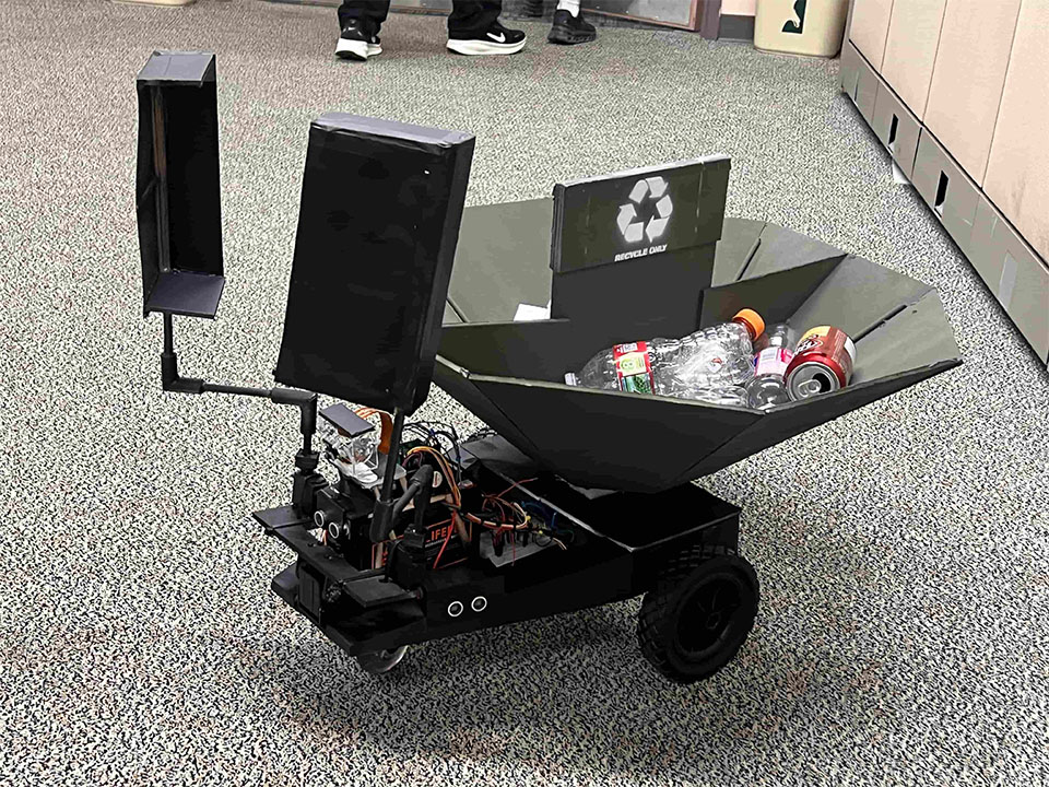 A robot with two scoopers attached to the front and a basket in the back for catching trash