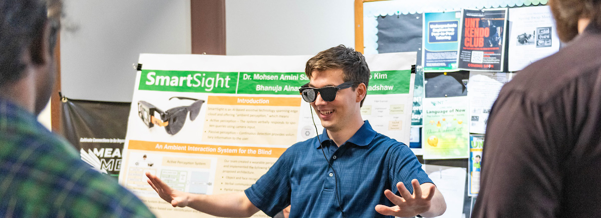 A student showcasing his project in front of a poster