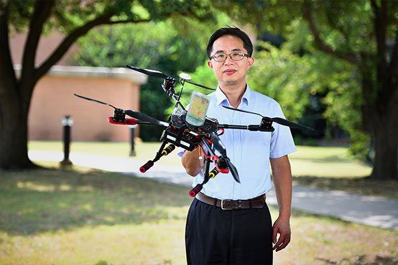 Dr. Shengli Fu standing outside with a drone in hand