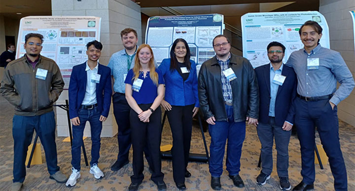 UNT students and Dr. Kaul pose in front of posters