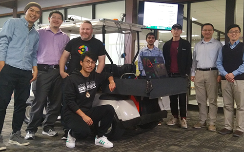 Yang and Fu posing with students in front of golf cart converted autonomous vehicle