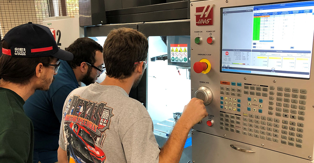 Students focuses learn how to operate a CNC machine