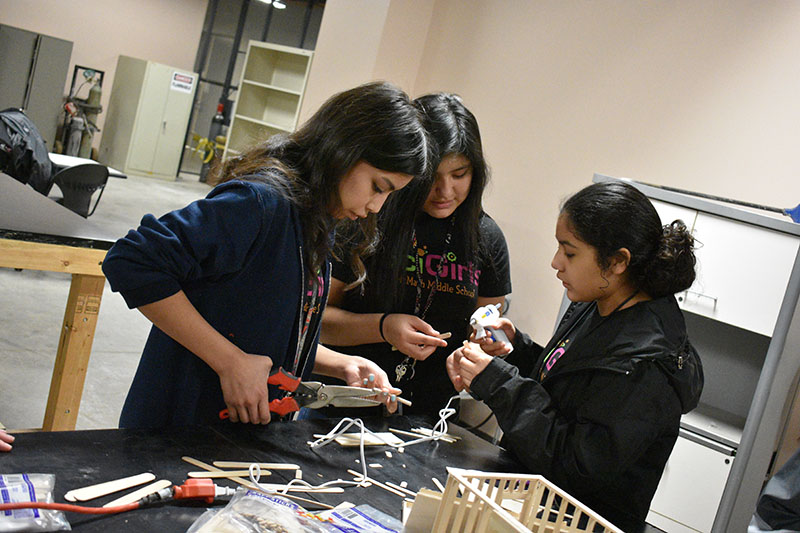 Three middle school girls participating in engineering activities.