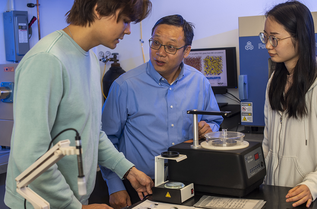 Jincheng Du and two students talk in the lab