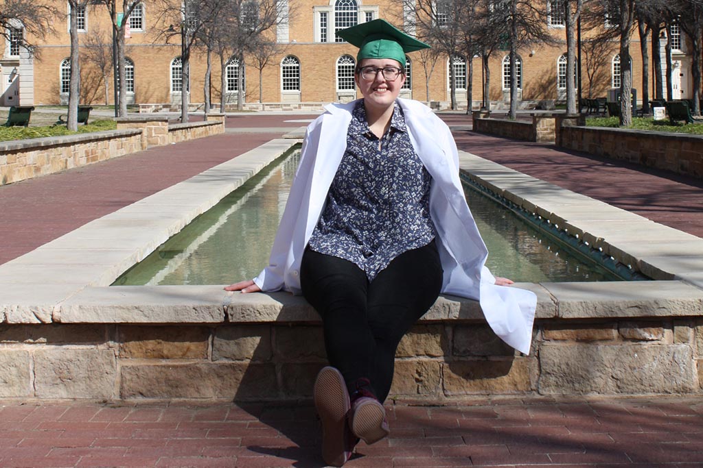 Kelly Jacques sits on the fountain ledge in front of the Hurley Administration Building.