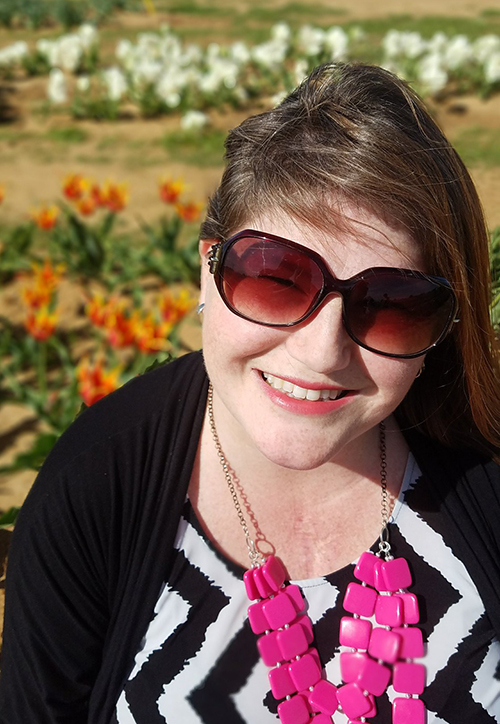 Melanie Dewey sits in a tulip field smiling
