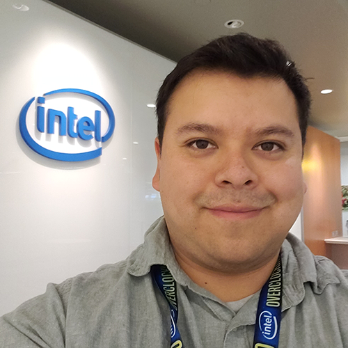 Jose Barcenas stands in an Intel office with the Intel logo in the background.
