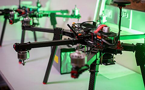 Two black drones on a table with green light shedding from behind
