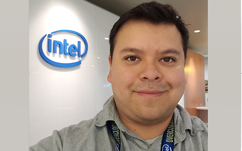 Jose Barcenas stands in an Intel office with the Intel logo in the background.